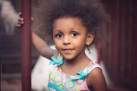 A Young Girl With Frizzy Brown Hair Smiling Sweetly" by Stocksy Contributor  "Anya Brewley Schultheiss"