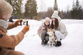 冬の森で一緒に野外散歩を楽しみながら、犬と一緒にかわいい娘と妻の写真を撮る父の肖像画、コピースペース の写真素材・画像素材. Image  162490122.