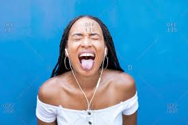 Find & download free graphic resources for tongue out. Woman Listening Music While Sticking Tongue Out Against Blue Wall Stock Photo Offset