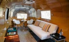 Vacances En Camping Car Airstream Avec Parement Bois Canape Blanc Table Appoint Design Et Chaises Eames Courant D Air Vacances En Camping Car Et Flux D Air Interieur
