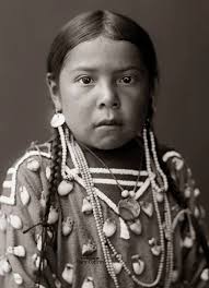 PRAIRIE BIRD,” 1905. The young girl, presumably Matilda Maud Prairie Bird  (1900-1960), was photographed by Richard Throssel at the Crow (Apsáalooke)  Reservation in Eastern Montana. Her dress was decorated with elk ivories.
