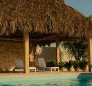 A thatched roof next to a swimming pool photo – Luxury Image ...