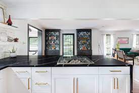 White kitchen cabinets with black countertops and gold hardware. Black Quartz Waterfall Countertop In A Black And White Kitchen Kitchen Design Remodel Black Granite Countertops Gold Kitchen Hardware Waterfall Countertop