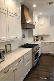 Neutral colored countertops and wooden open shelving keep this kitchen feeling natural. Shaker Style Kitchen With Stained Hood Shaker Style Kitchens Shaker Style Kitchen Cabinets White Shaker Kitchen Cabinets