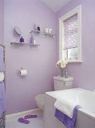 White and lavender bathroom features lavender walls framing inset framed medicine cabinet over white washstand topped with white marble countertop next to window covered in lavender roman shade over white tiled floor accented with gray border tiles. Lavendar Lavender Bathroom Purple Bathrooms Bathroom Decor