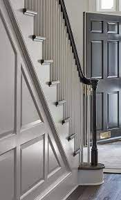 A Staircase Wall With Gray Wainscoting Features A Black Handrail With White Wood Spindles Around Dark Oak Fl Staircase Design Black Entry Doors White Staircase