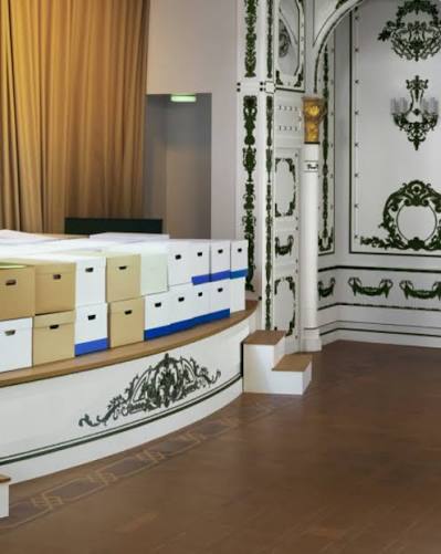 Thomas Demand builds everything twice. He finds an image, usually from news media, reconstructs the scene at life-size in paper and cardboard, photographs it with a large-format camera, and destroys the model.