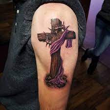 Cross tattoos are as eclectic as any out there, being found as stand alone art or as a piece of a larger work. Realistic Wooden Cross Tattoo With Barbed Wire And Purple Cloth