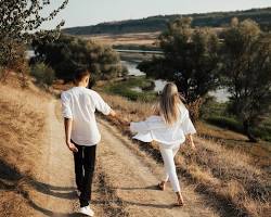 couple holding hands while walking through a scenic landscape