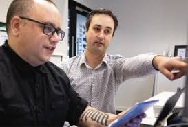 PROBLEM SOLVING- Company-X senior software architect Luke McGregor, right,  discusses a problem with Cory McKenzie