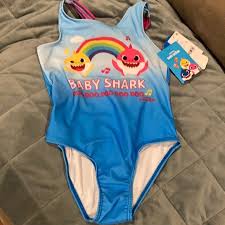 They'll be singing along to baby shark doo doo doo doo doo doo at the beach and pool in this cool baby shark swimming costume featuring a vibrant summer print of baby shark with mama and daddy shark surrounded by palm trees and contrast pink shoulder straps. Swim Girls Bathing Suit Baby Shark Poshmark
