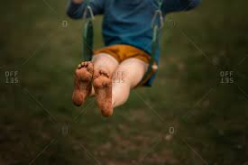 Seated young boy with dirty feet laughing. Dirty Feet Stock Photos Offset