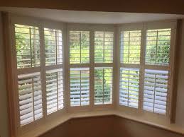 Angled bay window and door with plantation shutters fitted. Barnet Shutters Bay Window Made To Measure