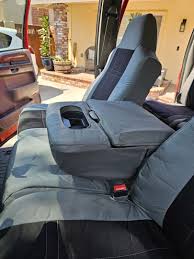 A professional auto upholsterer carefully stretching new material over a car seat frame