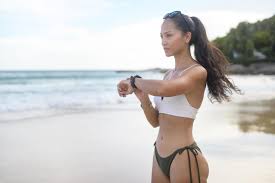jovem mulher bonita de biquíni relaxando e usando smartwatch na praia,  verão, férias, feriados e conceito de saúde. 9283636 Foto de stock no  Vecteezy