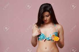 A Young Beautiful Slender Asian Girl In A Blue Swimsuit Thought About Her Small  Breasts On A Pink Isolated Background Stock Photo, Picture and Royalty Free  Image. Image 148089247.