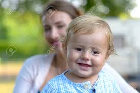 Happy Smiling Blond Baby Boy Outdoors In A Close Up Head And Shoulders Portrait With Mother Hidden Behind Him Stock Photo Picture And Royalty Free Image Image 106211898