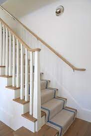 A Beige Staircase Runner With Blue Border Stripes Covers Stained Wood Treads That Match A Stained Wood Handrail Mounted At Wood Handrail Staircase Wood Railing