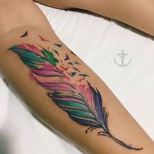 This tattoo includes a watercolor feather inked in black, blue, purple, and pink with black inked birds coming out of the feather. Tattoo By Felipe Bernardes Brazilian Tattoo Artist Feather Watercolor Tattoo Tatuag Feather Tattoo Colour Indian Feather Tattoos Watercolor Tattoo Feather