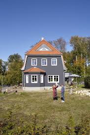 Das Rote Dach Lasst Die Dunkle Fassadenfarbe Leuchten Die Holzfenster Mit Sprossen Heben Die Bautraditionen Hervor Fassade Haus Haus 1930 Haus