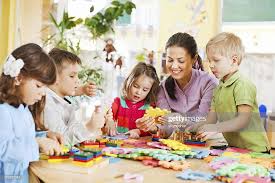 Group Of Kids Playing Together With Their Young Nursery Teacher Nursery Teacher Teacher Resources 21st Century Skills