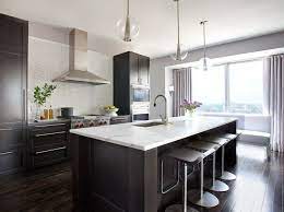 This white kitchen by soda pop design feels thoroughly contemporary thanks to its sleek cabinets and quartz waterfall kitchen island. This Or That White Vs Wood In Two Stylish Kitchens Cococozy Wood Floor Kitchen Dark Wood Kitchens Dark Wood Kitchen Cabinets