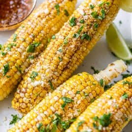 Corn on the cob grilling over charcoal for Mexican street corn
