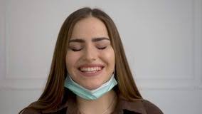 A Beautiful Girl Takes Off Her Medical Mask and is Happy. she Has a Smile  and a Laugh