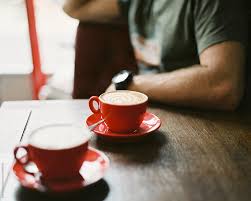 Choosing the perfect coffee table: Two Cups Of Coffee On A Wooden Table In A Cafe With A Man In The Background By Suzi Marshall