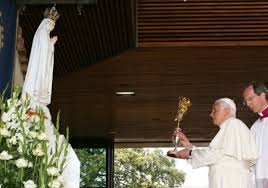 Pope raising a chalice to a statue of Mary