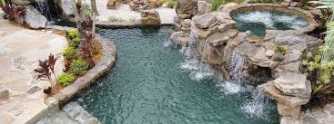 Ultra modern water feature and pond design. Natural Stone Grotto Waterfall With Elevated Spa