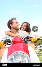 Young couple driving scooter in love. Joyful mixed race couple having fun  together outside driving motorcycle scooter. Free happy interracial couple  Stock Photo - Alamy