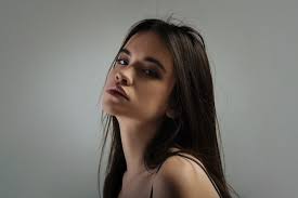 Reconsidering. Beautiful earnest long-haired young woman thinking and  looking down and wearing a top