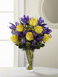 Sunlit Yellow Roses Are Arranged With Deep Purple Iris And Lush Greens Presented In A Lavender Designer G Flower Arrangements Beautiful Flowers Spring Flowers