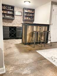 Simply sand and stain a 1×6 pine board, add a customized message and/or map, and mount a bottle opener on the board. Basement Dry Bar Ashley Diann Designs