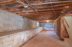 The exposed ceiling joists are painted a deep charcoal, the concrete floor is a fun red, and wood shelving and furniture add interest and utility. The Benefits Of Having A Finished Basement Advantage Contracting