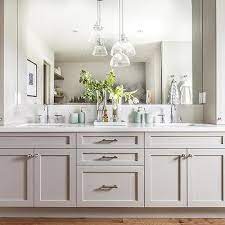 After incorporating subtle accent lighting in the room, hang a single pendant between two sconces on either side of the mirror, or use a ceiling light with dual pendant lights framing the mirror to provide ideal lighting in the bath. Bath Vanity With Staggered Hanging Lights Design Ideas
