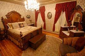 Victorian Style Bedroom Lots Of Curved Lines Elaborate Furnishing And Drapery Dark Wood Finishes Floral Designs On Wallpaper Bed Set And Rug