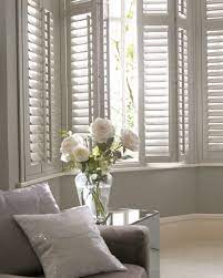 Welcoming living room boasts a light blue buffalo check sofa placed beneath a window covered in white plantation shutters layered behind white curtains. Pin By Danielled On Living Room Decor Ideas Home Living Room Home Decor White Shutters