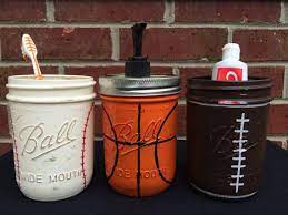 Crafted from manufactured wood with a white or espresso finish, this piece sports three open shelves, as well as an additional shelf below the cabinet door. Sports Theme Bathroom Decor Baseball Football Basketball Bathroom Decor Soap Dispenser Hand Pai Mason Jar Bathroom Decor Boys Bathroom Decor Sports Bathroom