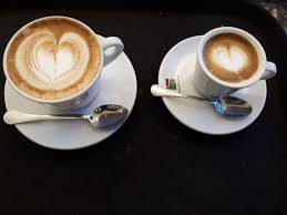 Vista dall'alto di tazza con cappuccino vicino cucchiaio e cubetti di zucchero su sfondo di legno bianco. Grazie Di Cuore A Tutti I Baristi Iobevominuto Minuto Caffe