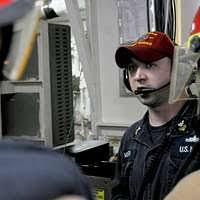 Electronics Technician 2nd Class Terry McLaughlin stands guard as crew  members from an oil tanker are escorted to a holding area.