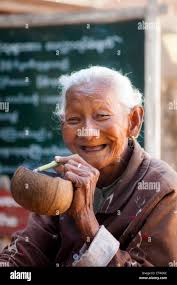Happy, old Burmese woman smiling while smoking a cigar in Bagan, Myanmar  Stock Photo