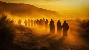 In biblical times, a group of people walks along a dirt path