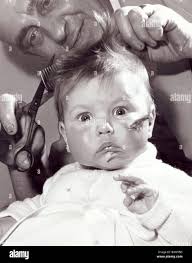 Three month old baby girl Susan Sinclair of Lanarkshire Scotland has a  haircut at her local barber shop January 1959 Stock Photo