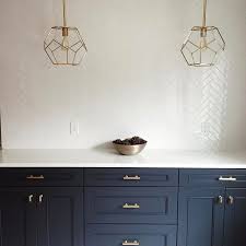 This gorgeous retro style kitchen is placed in the middle of an open layout, making it directly accessible from the other parts of the house. Navy Blue Cabinets With Herringbone Tile Backsplash Herringbone Tiles Kitchen White Kitchen Tiles Lake House Kitchen