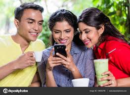 Indian girl showing pictures on phone to friends Stock Photo by ©Kzenon  139243790