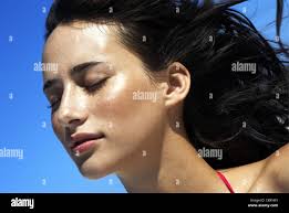 Female, long brunette hair, freckles, eyes closed, glowing skin, blue sky  Arnold Stock Photo