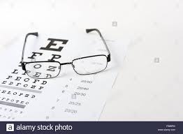 eye glasses on eyesight test chart background close up stock