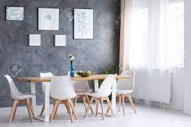 Kitchen & dining room furniture. Bright Dining Room With Wooden Table And White Chairs Against Concrete Wall With Paintings Stock Photo Picture And Royalty Free Image Image 90323974